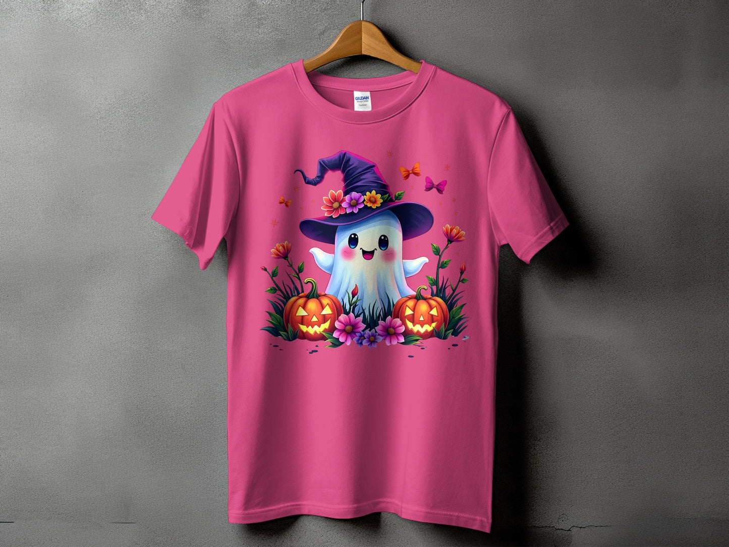Pink t-shirt with a cute ghost wearing a witch hat, surrounded by pumpkins and flowers.